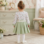 Back view of baby girl wearing sage green frock suit with white pajama and floral top
